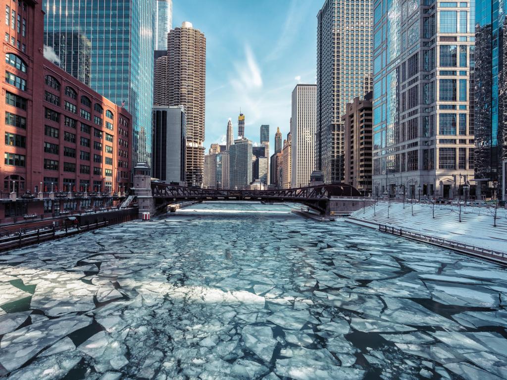 In between tall buildings a river with bridges crossing is almost frozen over