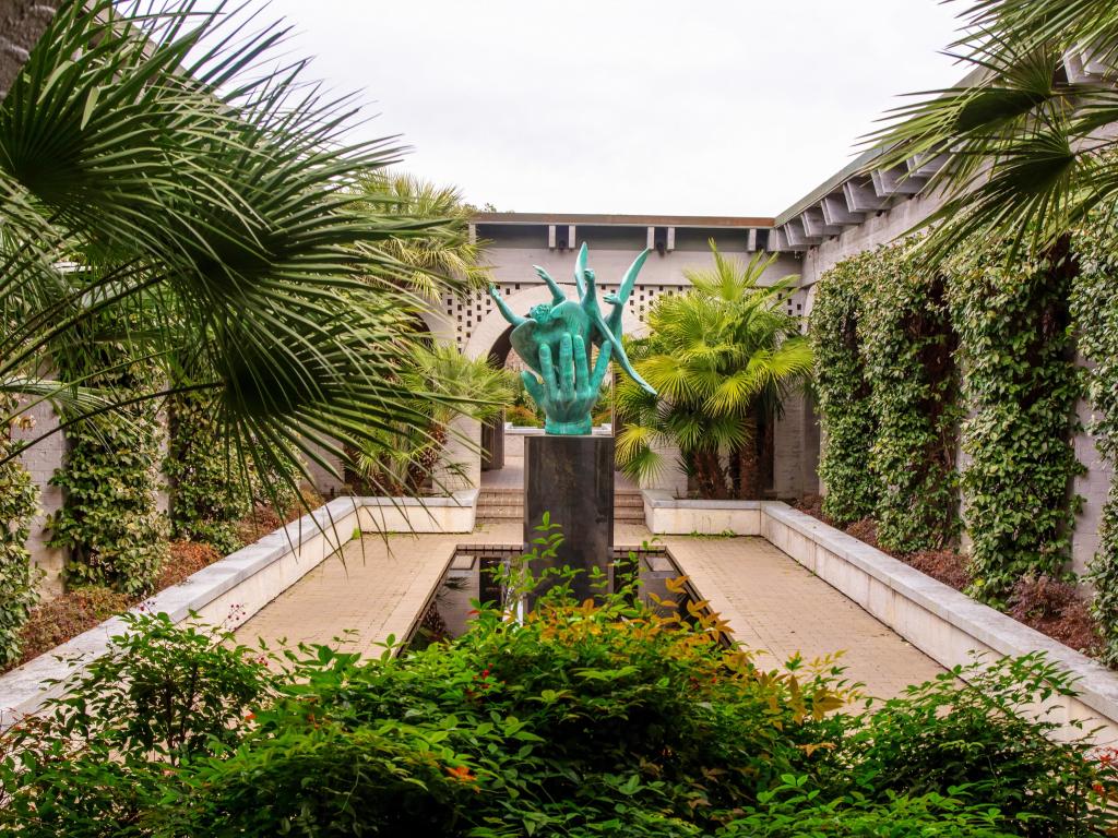 Statue and pool at renowned Brookgreen Gardens, a bronze statue surrounded by palms and ivy in landscaped garden.