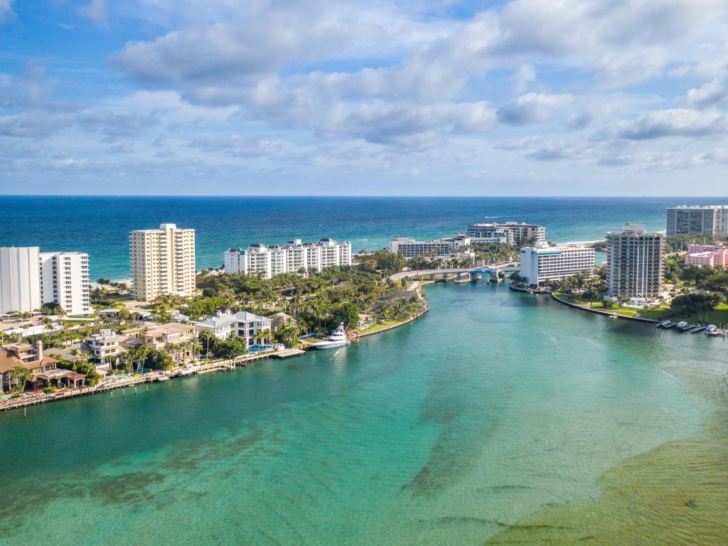 Boca Raton, Florida, USA taken as an aerial view of the lake, city buildings and sea beyond on a sunny day.