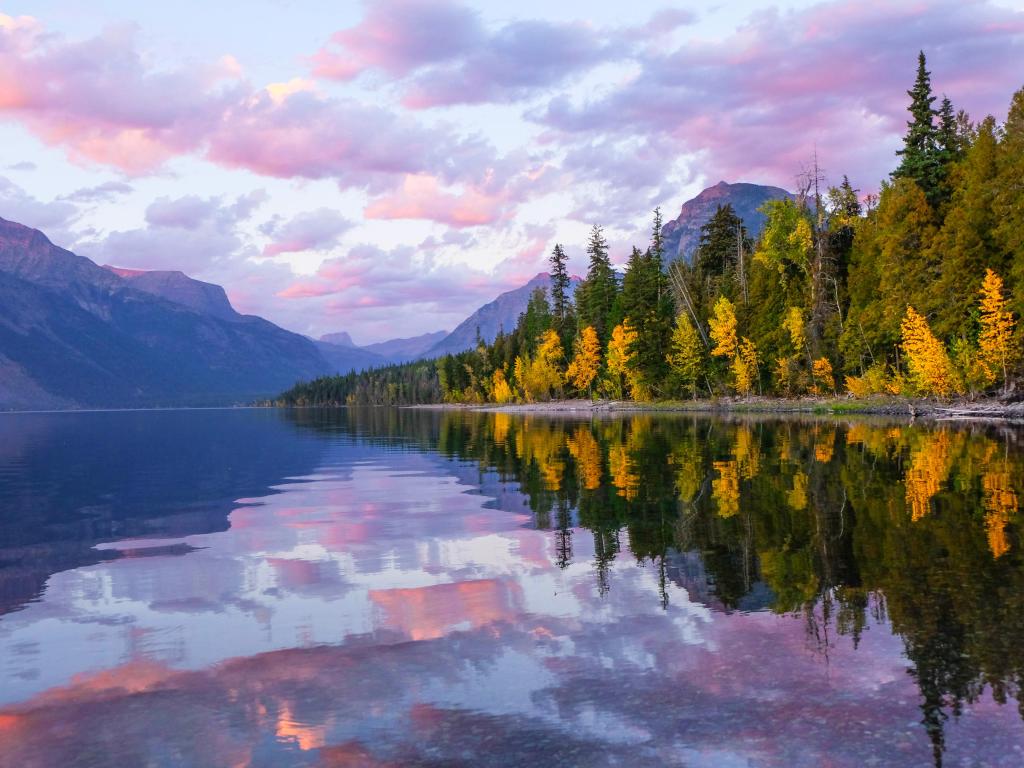 Lake McDonald, Glacier National Park, Montana, USA at sunset with trees and mountains in the distance.