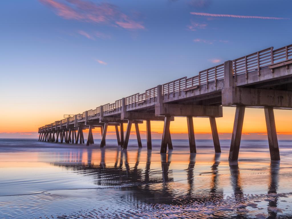 Jacksonville, Florida, USA with a beach view and Jacksonville Pier taken at dawn with a calm sea and stunning sky.