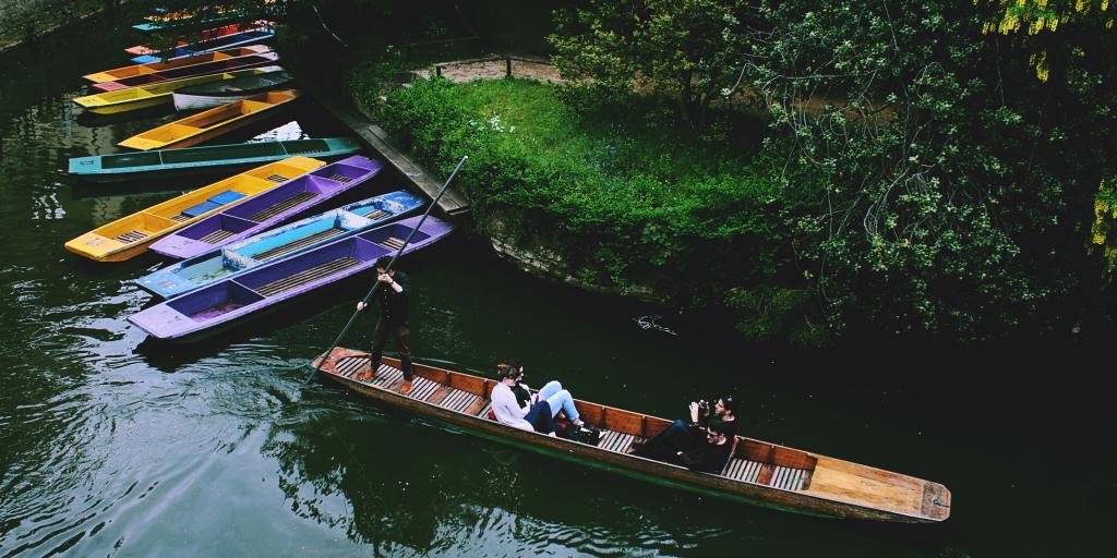 People punting in Oxford next to colourful boats 