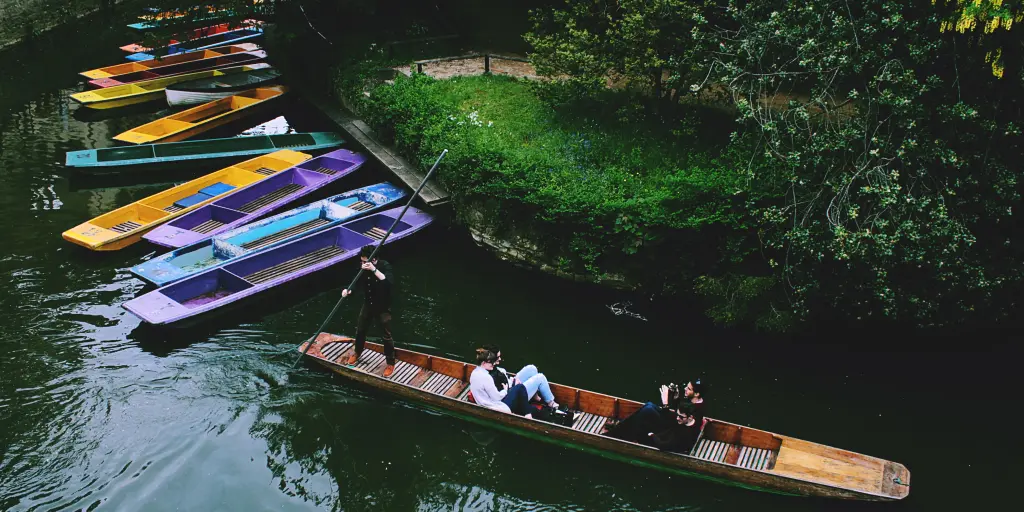 People punting in Oxford next to colourful boats 