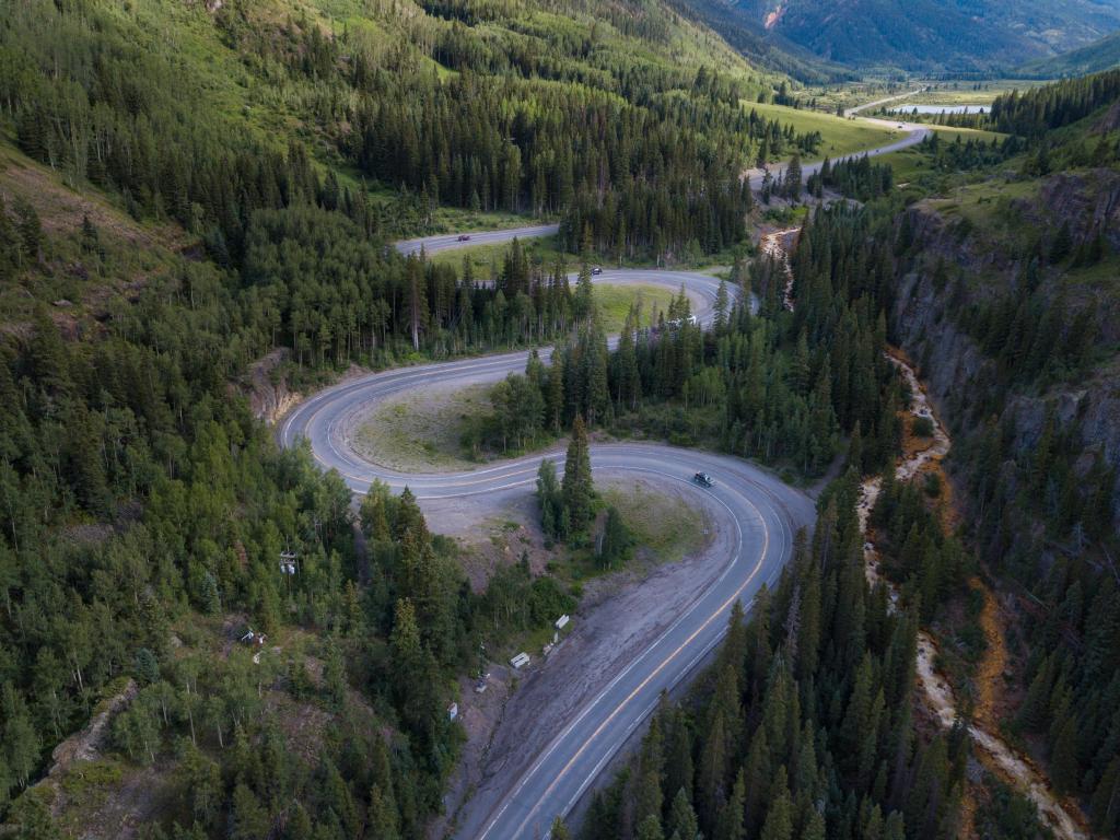 The Million Dollar Highway, Colorado snakes its way through a valley, surrounded by forest and mountains