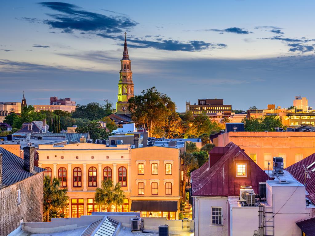 Low rise buildings with a church spire in the background in many colours under sunset light