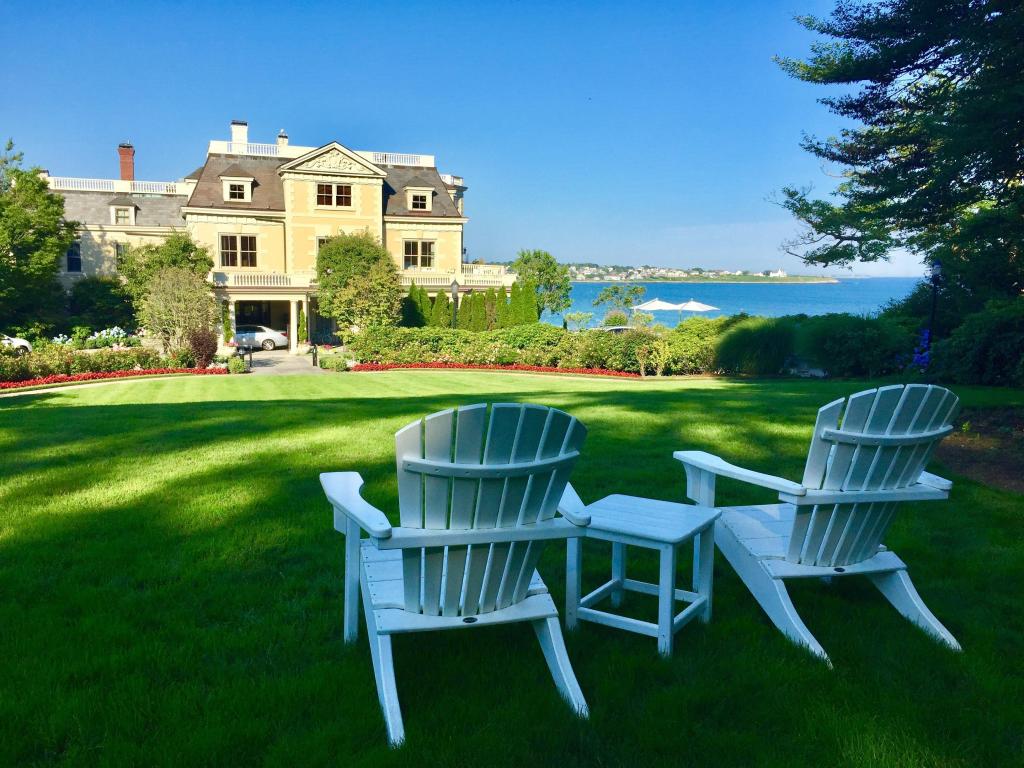 Wooden chairs stand on the law outside a mansion by the ocean in Newport, Rhode Island