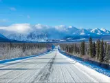 Alaska Highway through the forests of Yukon heading towards mountains in the winter