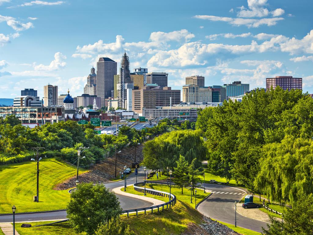 Hartford, Connecticut, USA downtown cityscape with green foliage in the foreground and the city skyscrapers in the distance taken on a sunny day.