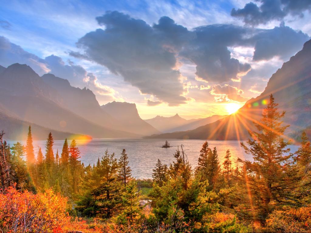 Glacier National Park, Montana, America taken at Saint Mary Lake and Wild Goose Island, with fall trees in the foreground, the lake and mountains faint in the distance at sunset. 