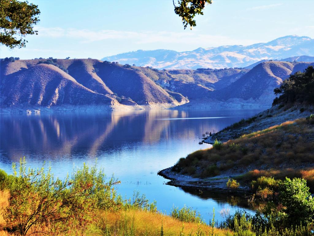 Cachuma Lake under a blue sky with snow-topped mountains in the distance 