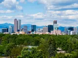 Denver, Colorado, USA with skyscrapers in the distance and greenery in the foreground.