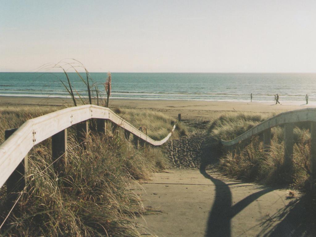 Paraparaumu Beach, New Zealand with sand dunes and a wooden path leading to the sea. 