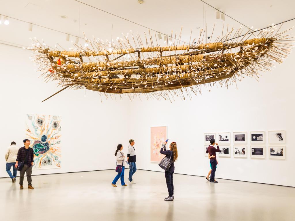 An art installation hanging from the ceiling in a white exhibition room