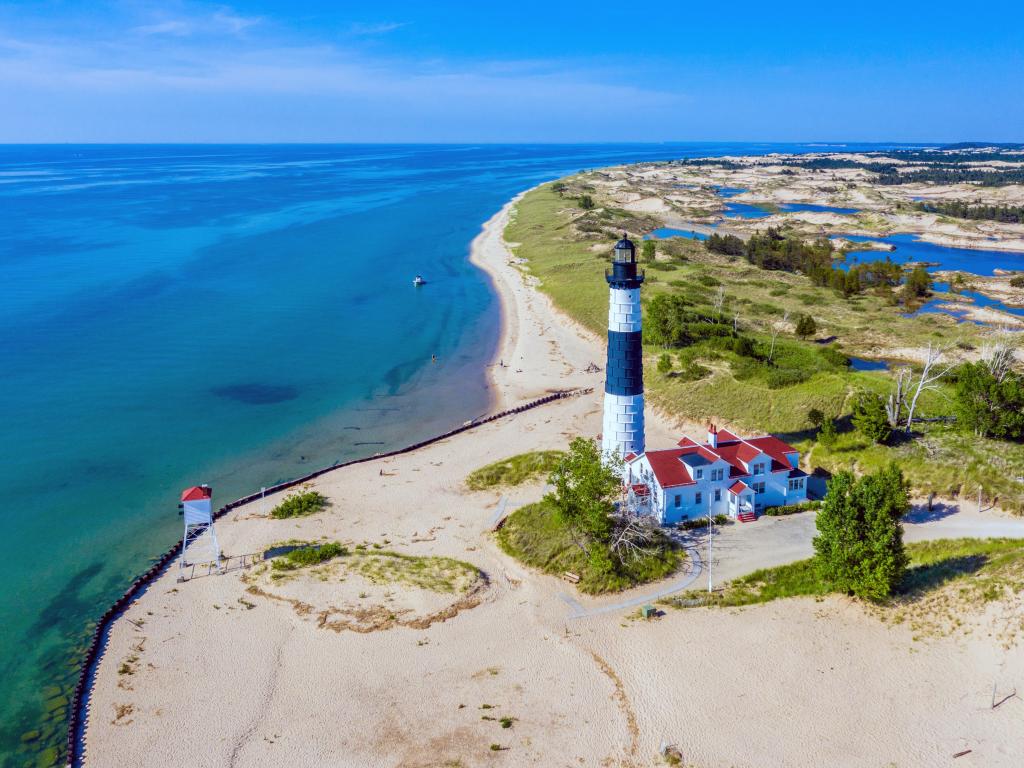 Light house on bright white sands next to the blue ocean