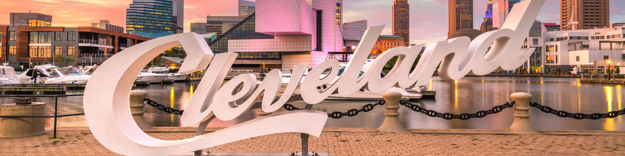 Skyline of downtown Cleveland from Voinovich Bicentennial Park during a sunset, the famous "Cleveland" sign is in focus