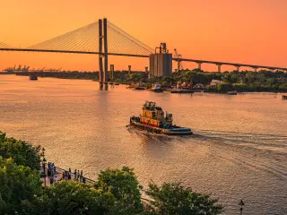 View of Talmadge Memorial Bridge and a tug boat on the river during sunset
