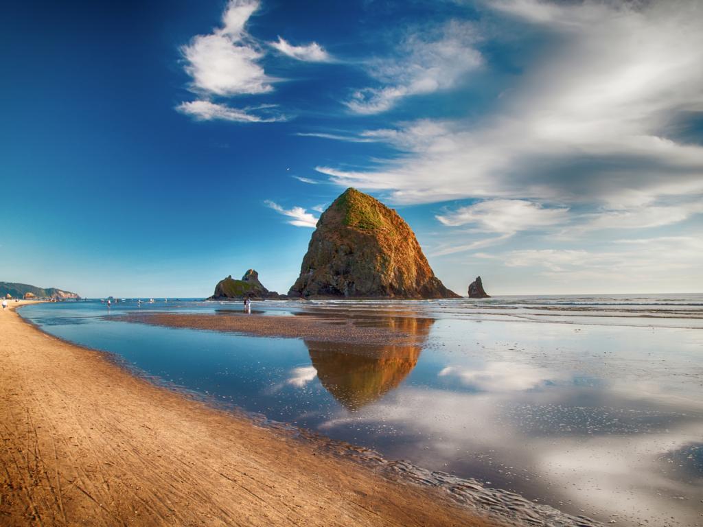 Haystack Rock and its reflection on the water in Cannon Beach, Oregon