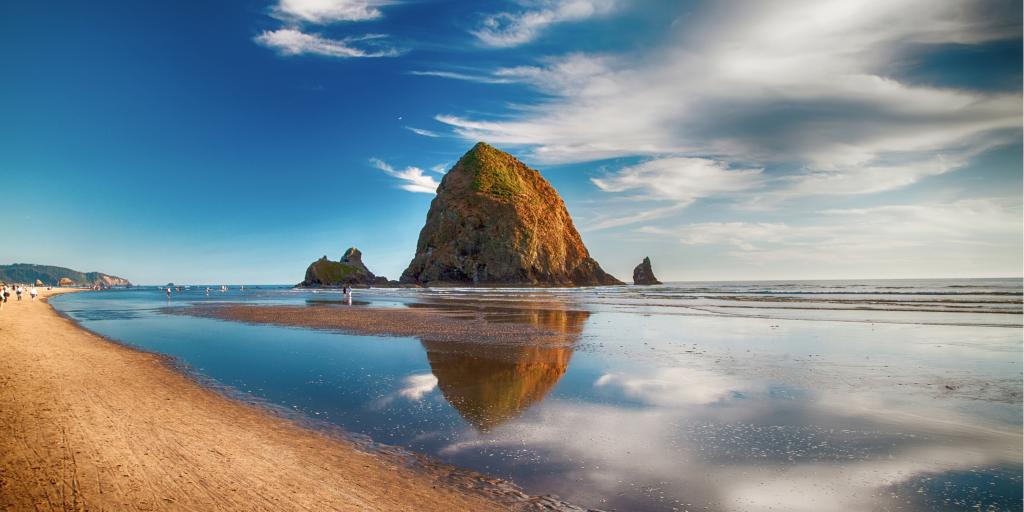 Haystack Rock and its reflection on the water in Cannon Beach, Oregon