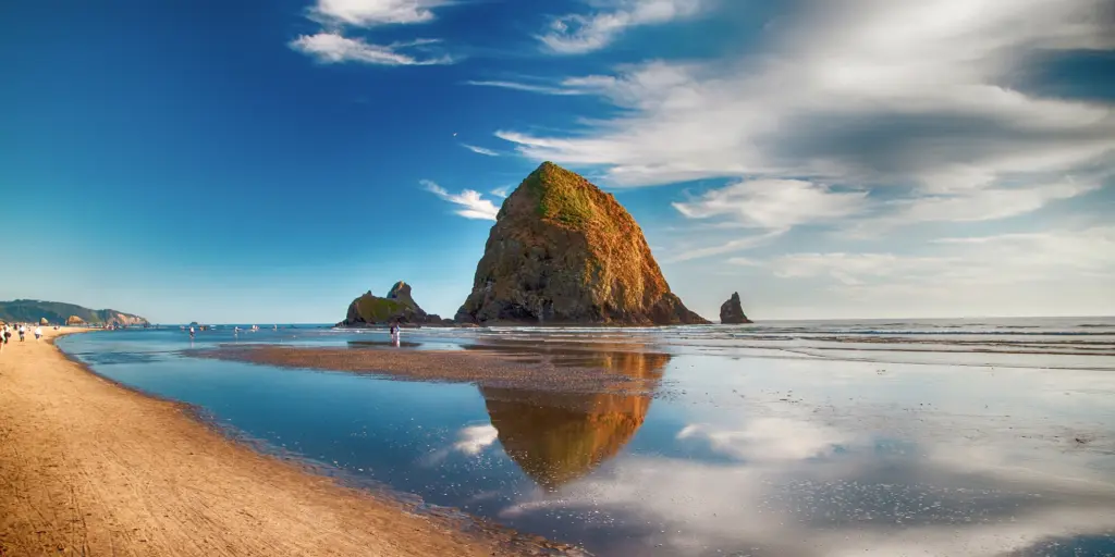Haystack Rock and its reflection on the water in Cannon Beach, Oregon