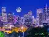 Denver skyline with lights on in the buildings and a big full moon in the sky