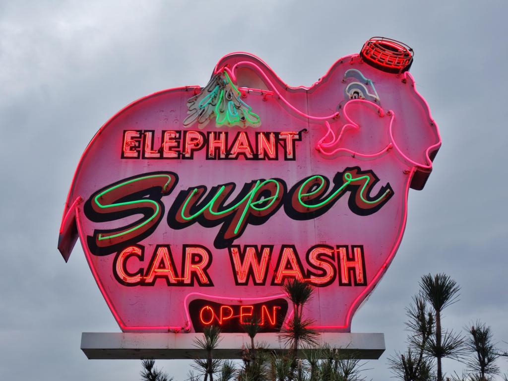 Big neon lit sign for the car wash service in Seattle on an overcast day