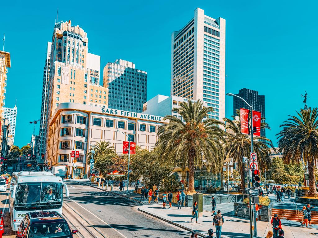 Sky scrapers, palm trees, pedestrians, blue sky at Union Square, San Francisco Downtown