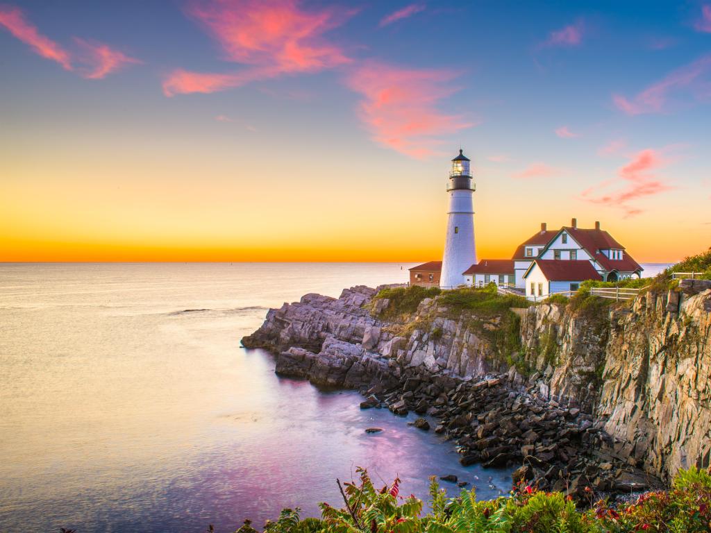 Cape Elizabeth, Maine, USA at Portland Head Light taken at sunset with a stunning sky, calm sea and the rugged coast under the lighthouse. 