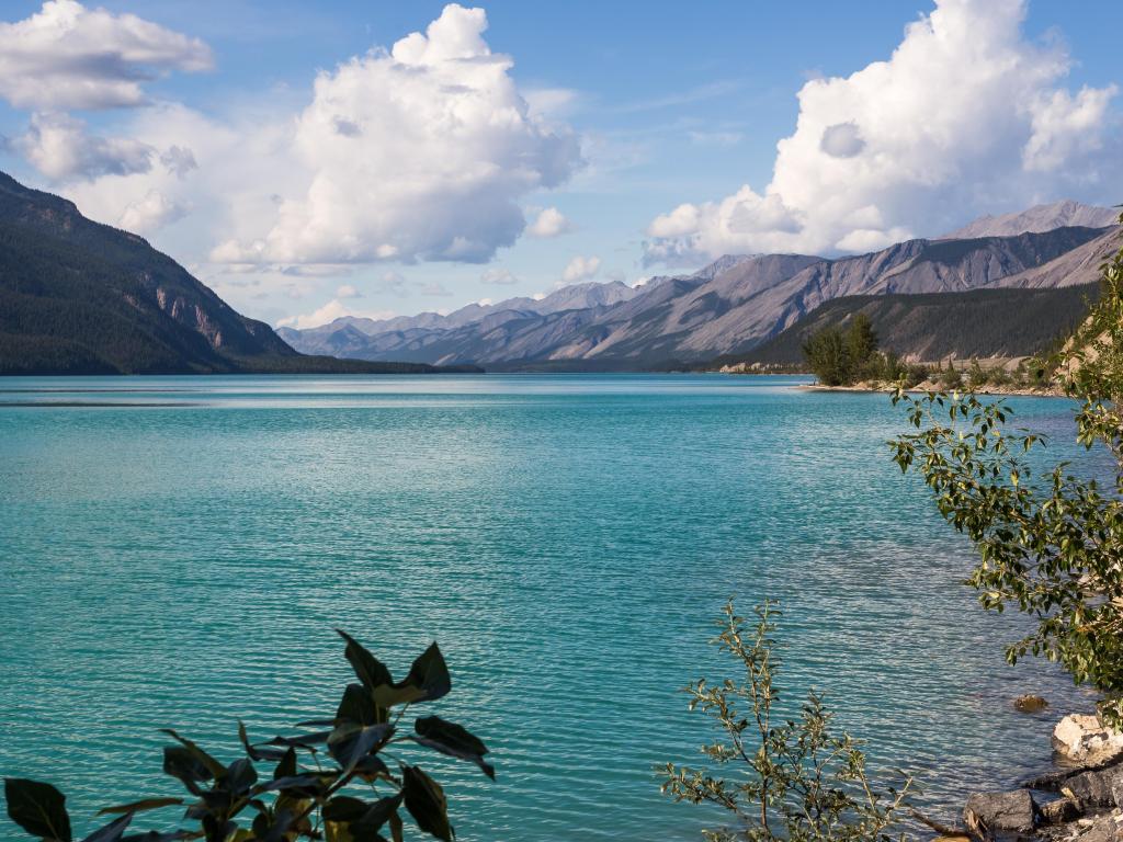 Muncho Lake in British Columbia, Canada with beautiful turquoise water and mountains in the distance. 