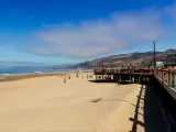 View across sandy beach and boardwalk at Pismo Beach, with bright blue skies and ocean in the background