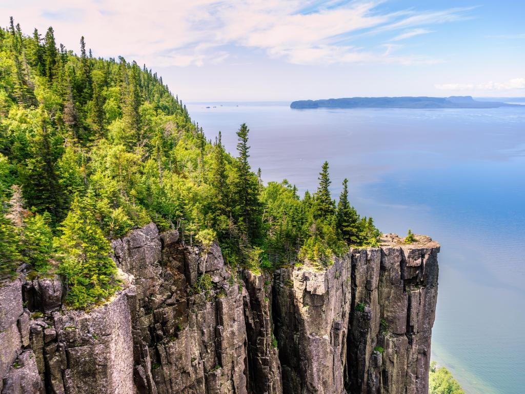 Lake Superior, Ontario looking from a mountain cliff covered in trees to the lake below on a calm, clear day. 
