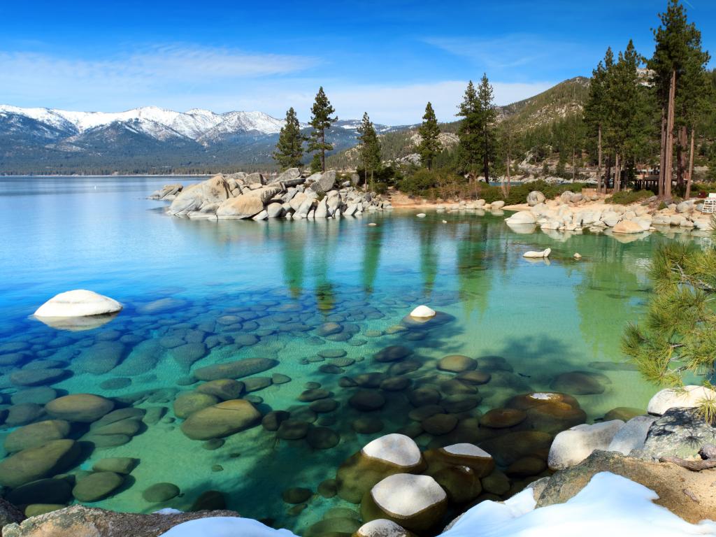 Clear waters of Lake Tahoe with snow covered mountain peaks in the background, California - Nevada border