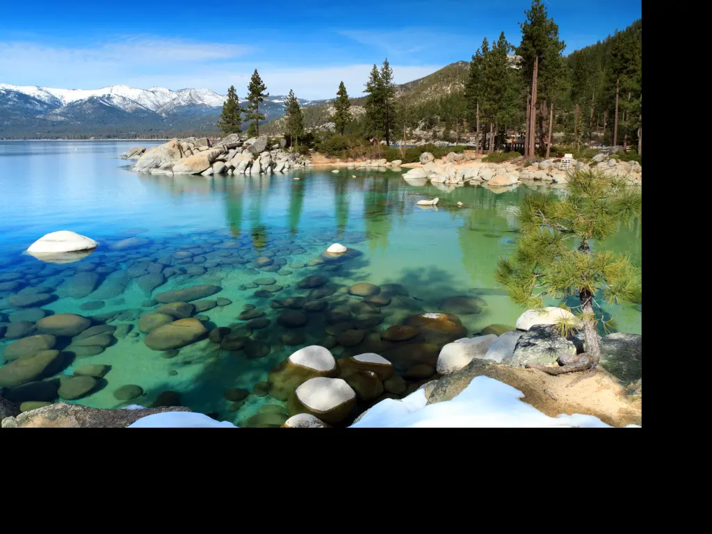 Clear waters of Lake Tahoe with snow covered mountain peaks in the background, California - Nevada border