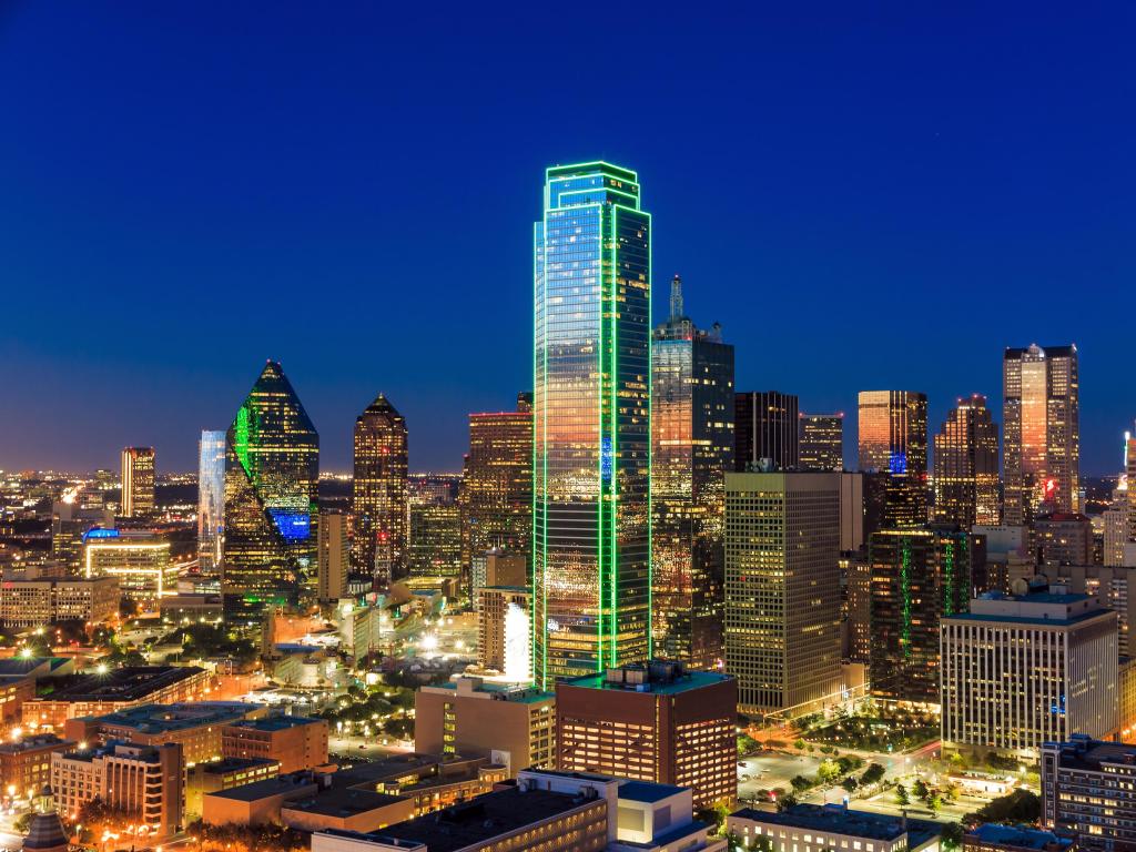 Dallas, Texas, USA with the cityscape at night against a blue sky.
