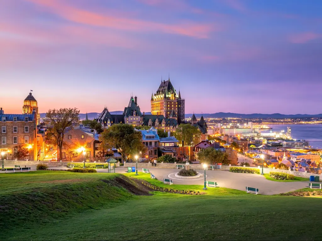 Quebec City, Canada taken as a panoramic view of the city skyline with Saint Lawrence river in the background and taken at early evening with a large grass area in the foreground. 