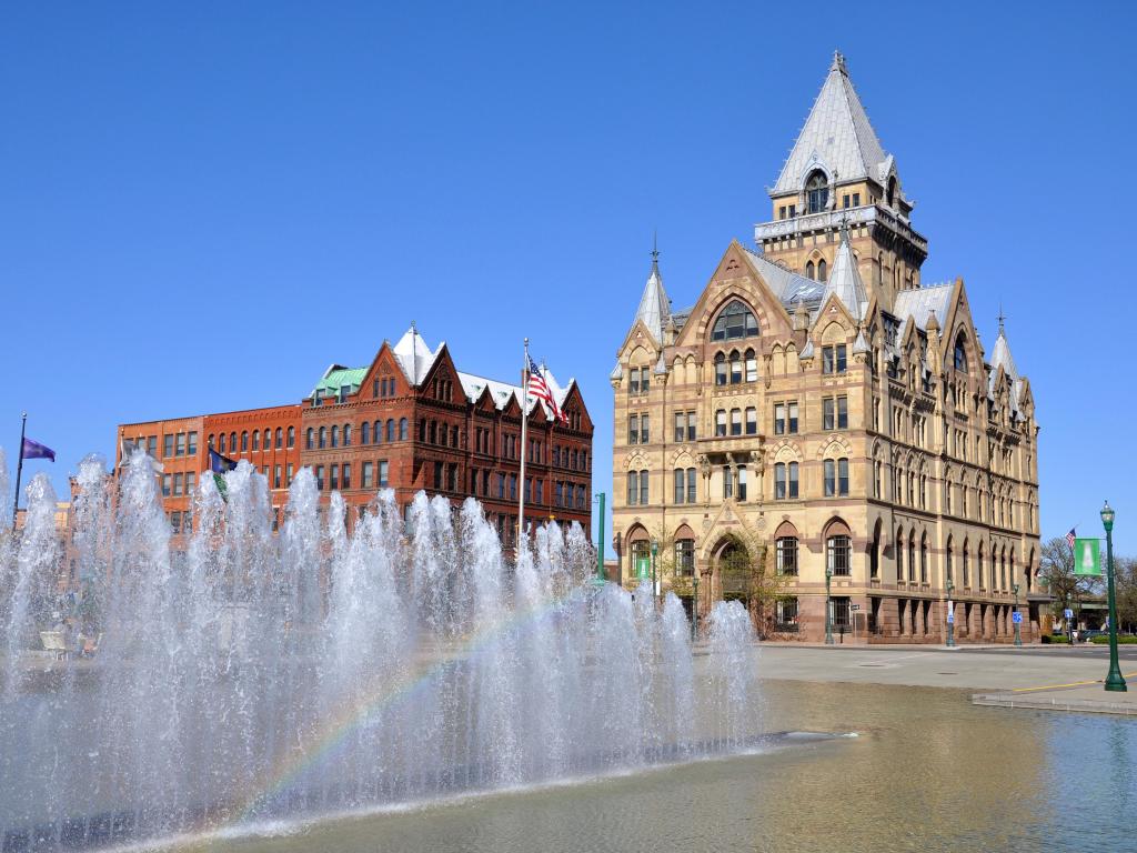 Fountain with rainbow in a square in front of ornate building