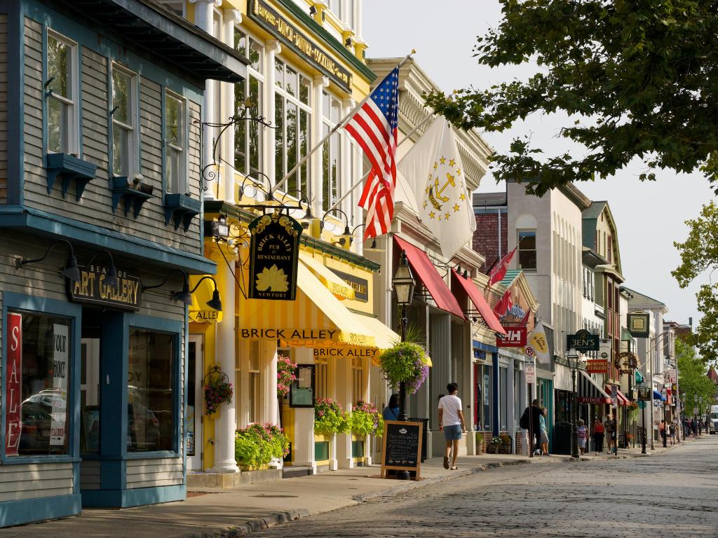 Colorful wooden buildings housing shops line the streets of historic Newport, Rhode Island. Flags in foreground