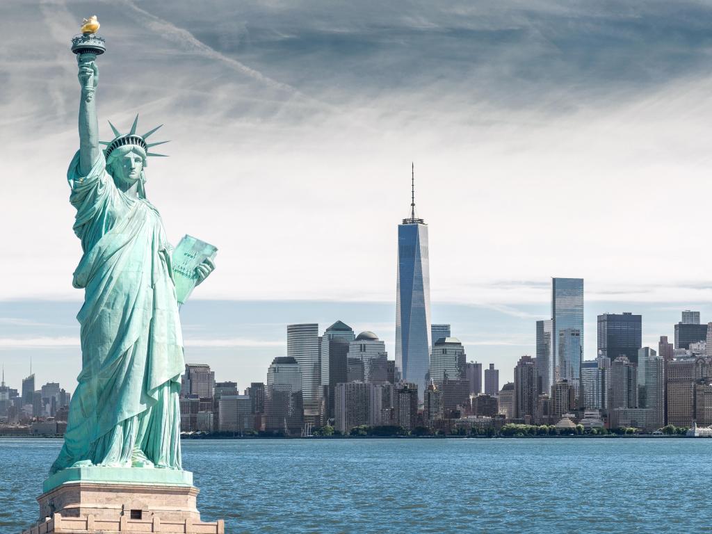 New York City Skyline with the Statue of Liberty in the foreground with the Hudson River and a grey sky above