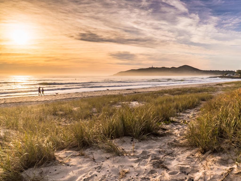 Sandy beach illuminated in golden sunrise light with mist rising off the sea