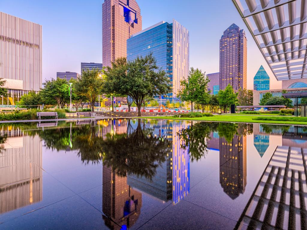 Dallas, Texas, USA downtown cityscape at twilight with water in the foreground reflecting the skyscrapers. 