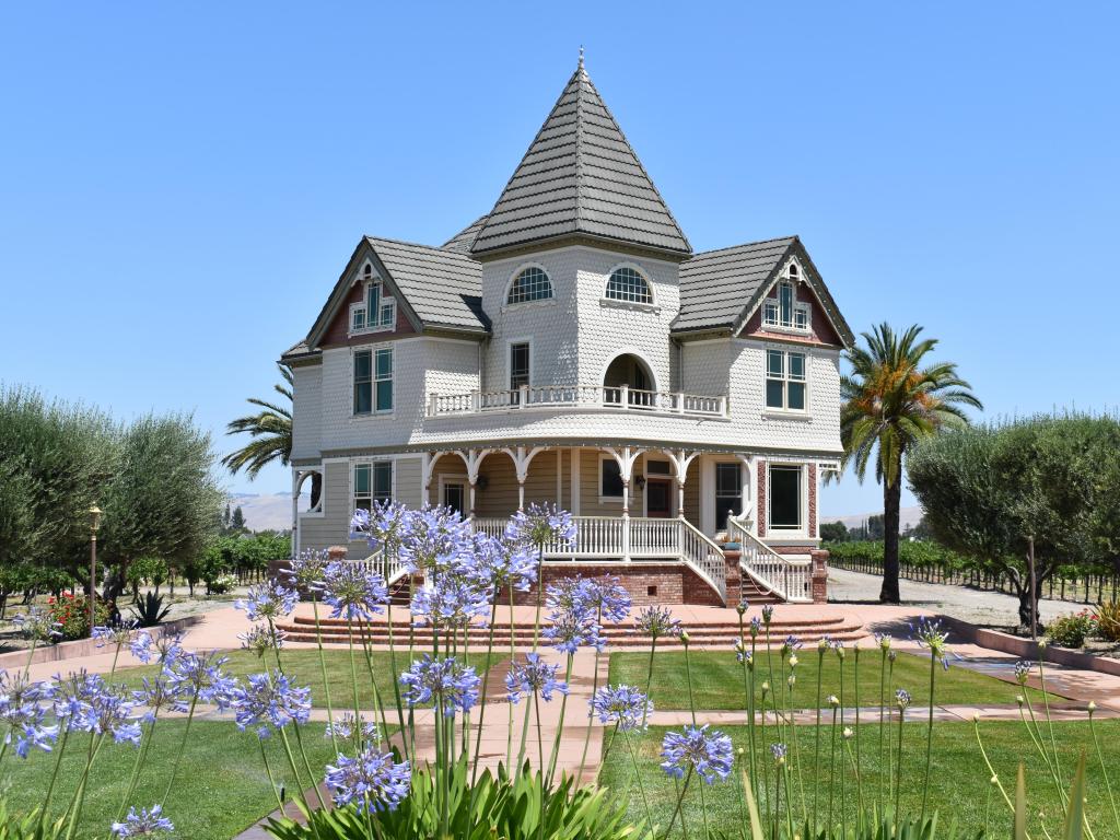 A Victorian style building at a winery in California, purple flowers in the garden in the foreground