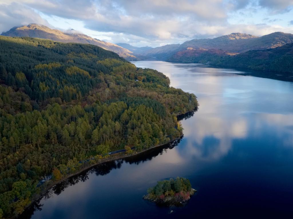 Aerial view of Loch Lomond in Scotland on an overcast day, with mountains and trees all around the water