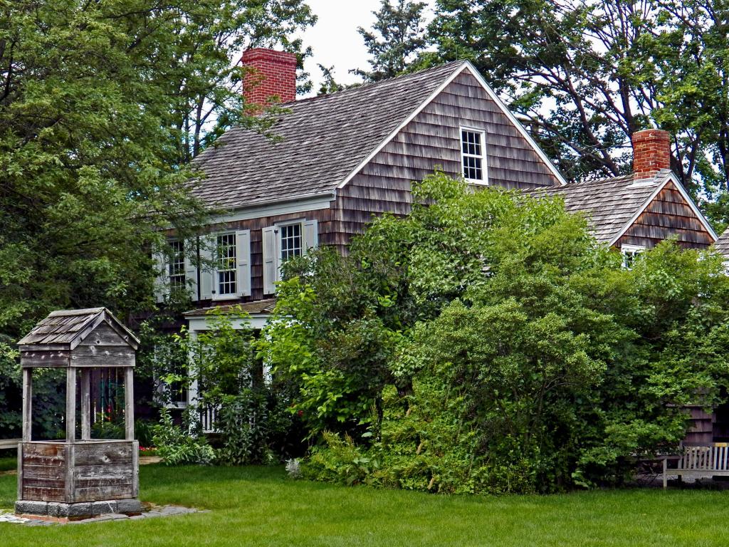 Poet Walt Whitman's birthplace in New York. There is a well in the house's garden, and the property is surrounded by trees.