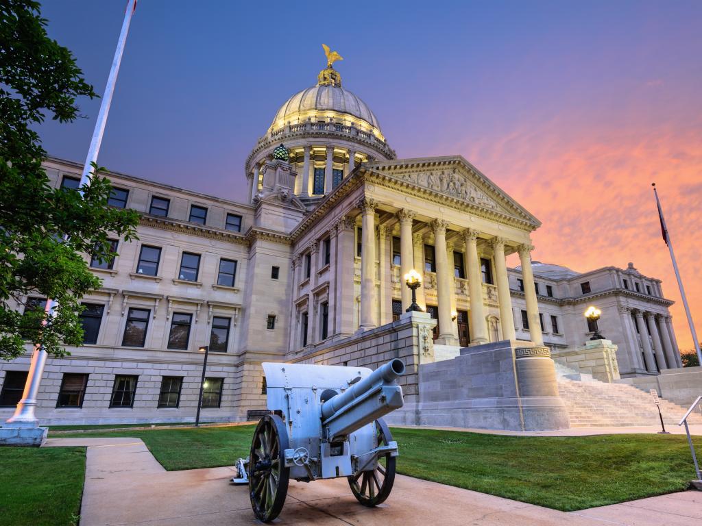 The State Capitol building in Jackson Mississippi with a classic cannon in front at sunset.