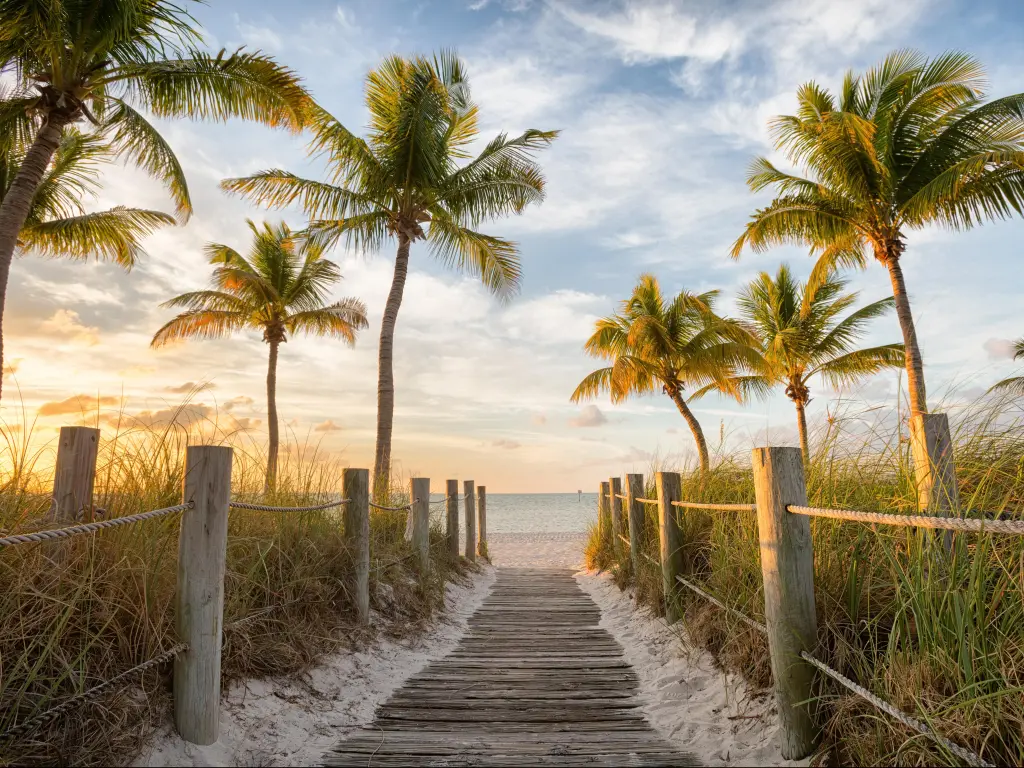 Sunrise at  Smathers Beach in Key West, wooden footbridge leading to the sand with palm trees either side