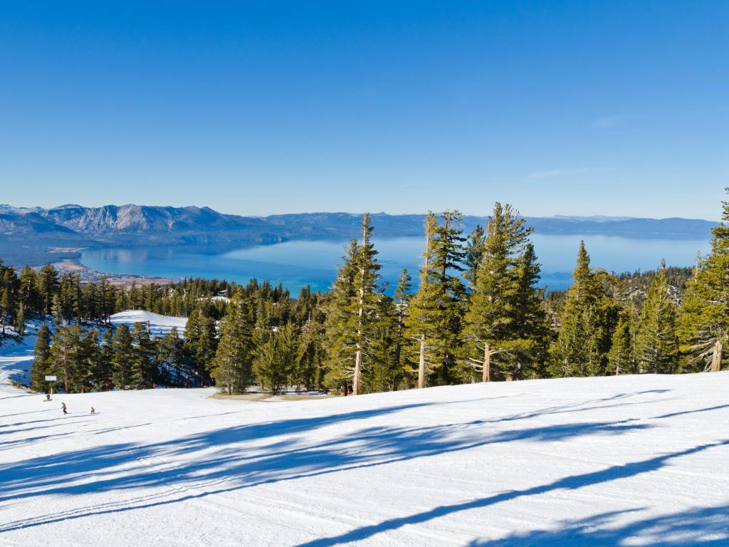 Skiing with Lake Tahoe with the lake and mountains in the background on a sunny winter day