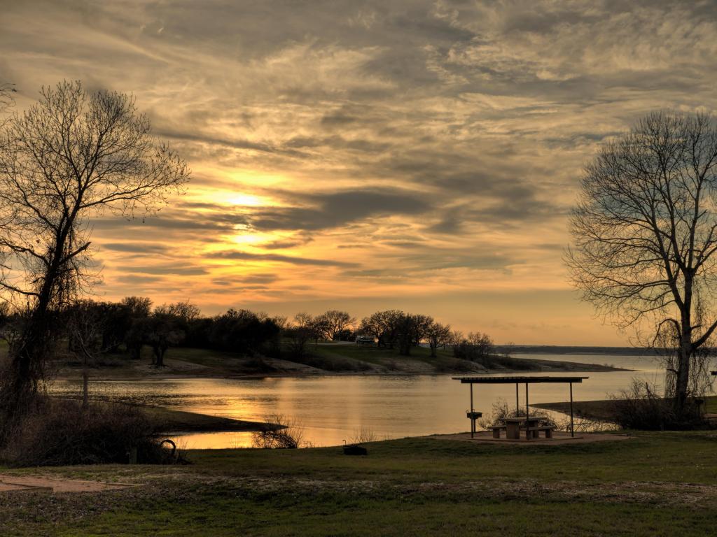 Beautiful, orange-hued sunset over Lake Whitney near Waco, Texas. The sun beams reflect on the lake.