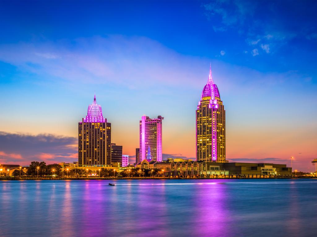Mobile, Alabama, USA with downtown skyline in the distance reflecting purple in the river in the foreground and taken at night.