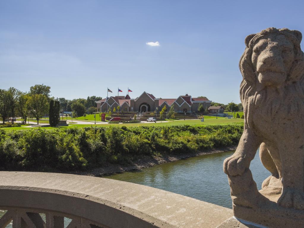 Museum in Cedar Rapids viewed from a distance on a bridge, a stone lion statue frames the image on the right