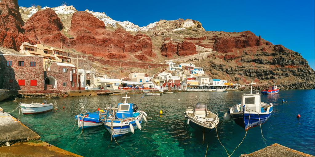 Fishing boats float in the Old port Amoudi of Oia village at Santorini island in Aegean sea, Greece