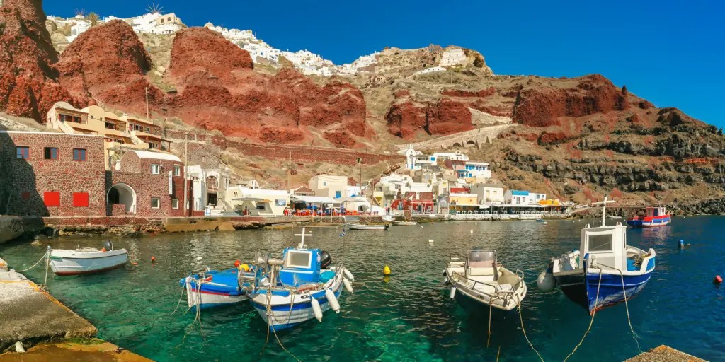 Fishing boats float in the Old port Amoudi of Oia village at Santorini island in Aegean sea, Greece